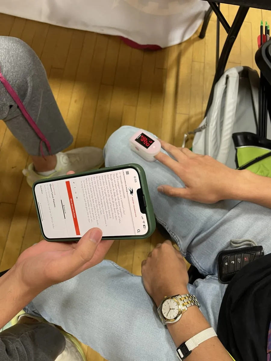 A finger in the heart rate monitor next to a phone